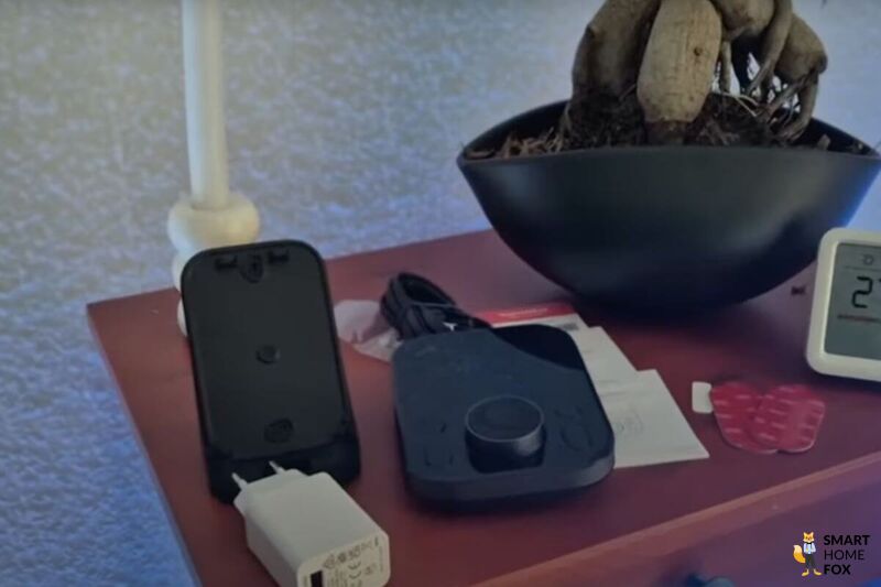 Im Test des SwitchBot Hub 3 ist der Lieferumfang auf einem kleinen Sideboard ausgebreitet und der besteht aus einem Kabel + Stecker, Halterung, Bedienungsanleitungen und ein paar Kleber.